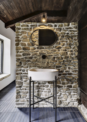 V přístavku domu je vybudovaná koupelna s toaletami. Moderní design tady dokonale ladí s kamenem a dřevem
